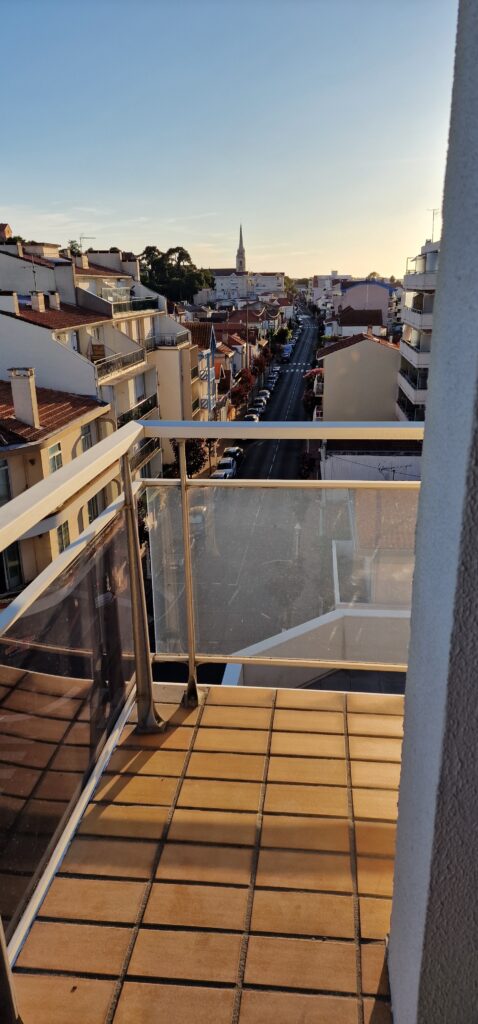 Vue d'un balcon sur les toits d'Arcachon et le clocher d'une église au loin. 